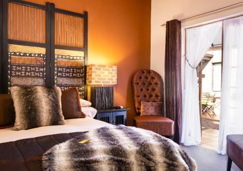 a bedroom with a bed and a chair and a window at Ama Zulu Guesthouse & Safaris in Hluhluwe