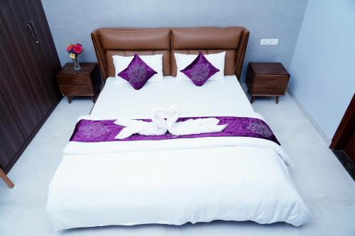 a bedroom with a bed with purple and white sheets at UNNATHI SUITES in Mysore