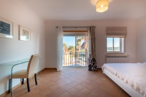 カザル・ダ・ラゴア・セッカにあるAcolhedora Vivenda Geminada Praia D'el Reyのベッドルーム1室(ベッド1台、デスク、窓付)