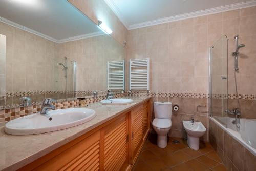 a bathroom with two sinks and a toilet and a shower at Acolhedora Vivenda Geminada Praia D'el Rey in Casal da Lagoa Seca