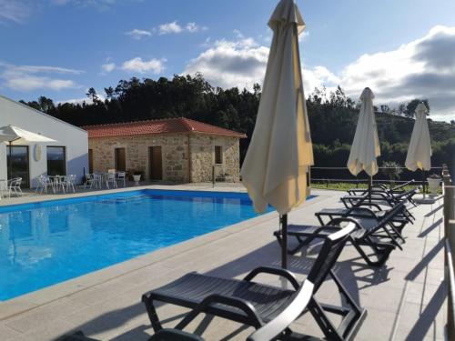 a swimming pool with lounge chairs and umbrellas at Quinta de Real in Valença
