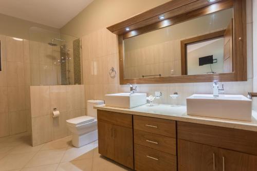 a bathroom with two sinks and a toilet and a mirror at 883 Residencial Casa Linda in Sosúa