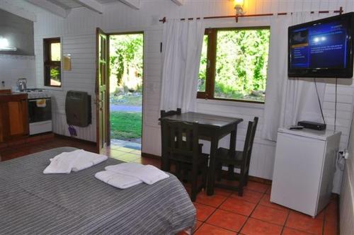 1 dormitorio con cama, mesa y TV en Cabañas y Hosteria Aldea Los Huemules en El Hoyo
