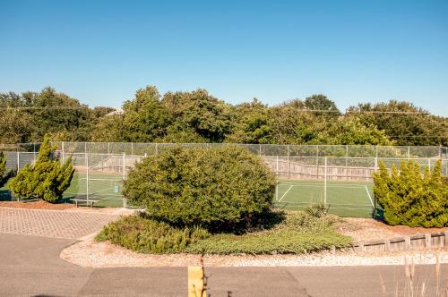 a tennis court with trees behind a fence at Christie in Duck