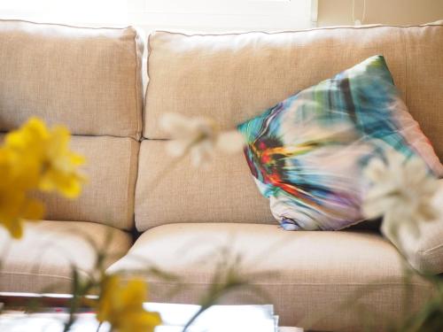 a pillow on a couch with flowers on a table at Hotel Noguera Mar in Denia