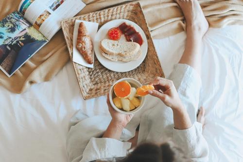 a person sitting on a bed with a plate of food at Hotel Noguera Mar in Denia