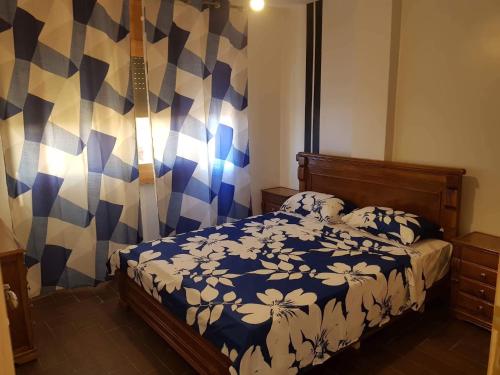 a bedroom with a bed with a blue and white comforter at Appartement Wynwood 3 in Oujda