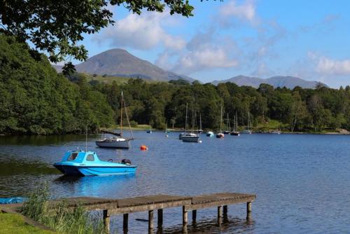 a group of boats on a lake with a dock at Bluebird Lodge in Coniston