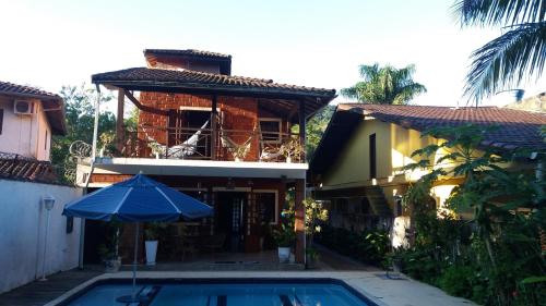 a house with a swimming pool and an umbrella at Casa praia Camburi com piscina in Camburi
