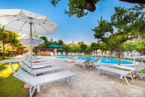 un gruppo di sedie a sdraio e un ombrellone accanto alla piscina di Hotel Antiche Mura a Sorrento