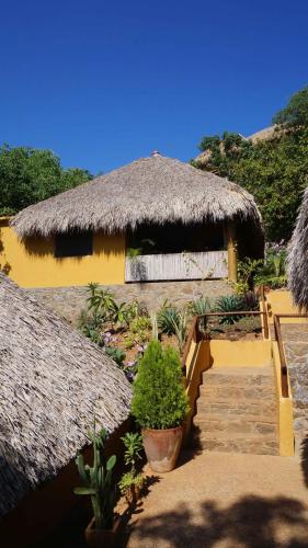 a house with a straw roof with a staircase and a building with a thatch at Casa Aditi in Mazunte