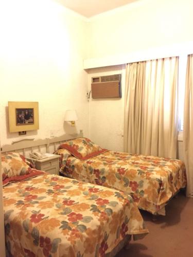 a hotel room with two beds and a window at Hotel Cervantes in Mendoza