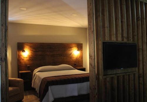 a bedroom with a bed and a flat screen tv at A Casinha da Padaria, Soajo in Soajo