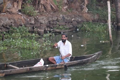 a man is rowing a boat in the water at Beach Paradise Day Cruise Houseboat in Alleppey