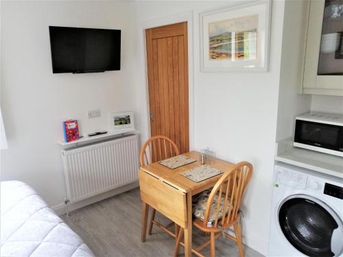 een kleine kamer met een tafel en stoelen en een magnetron bij BallyCairn Self Catering Studio in Larne