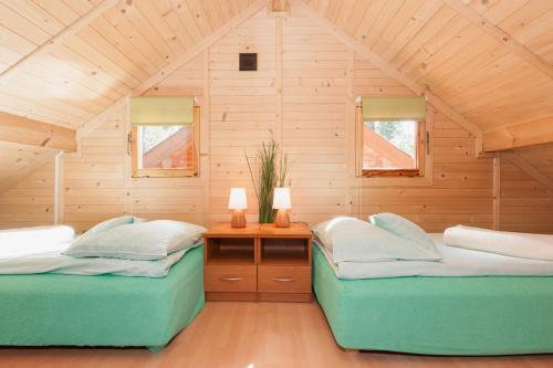 two twin beds in a room with a wooden ceiling at SOLEI in Pobierowo