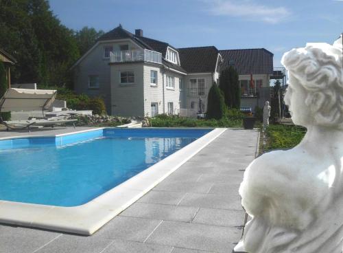 une statue d'une femme debout à côté d'une piscine dans l'établissement Villa Vogelsang VO3, Schwimmbad, Sauna, à Sierksdorf
