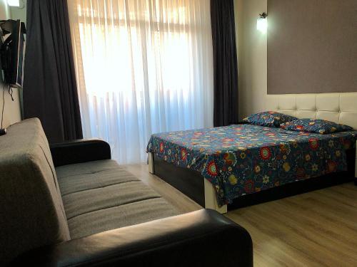 ein Schlafzimmer mit einem Bett, einem Sofa und einem Fenster in der Unterkunft Orbi Sea Towers Apartments in Batumi