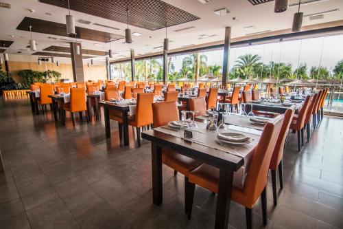 a dining room with tables and chairs with orange chairs at La Marina Resort in La Marina