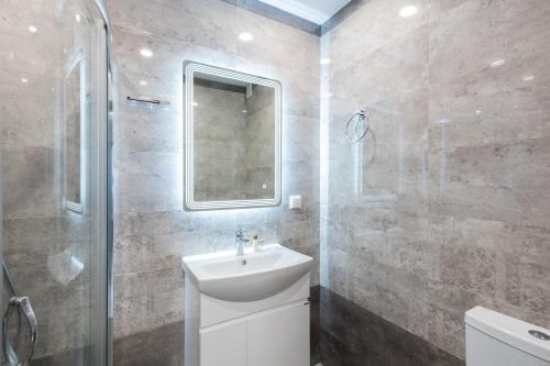 a bathroom with a sink and a shower and a mirror at SEA GARDEN PANORAMA APARTMENT in Burgas