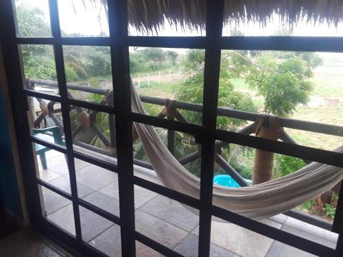 a hammock in a window with a horse in the background at Beach Front Guesthouse in Puerto Escondido