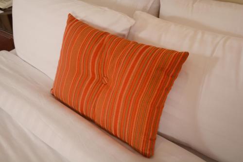 an orange striped pillow on a white couch at Islamabad Regalia Hotel in Islamabad