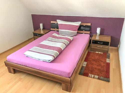 un grande letto con materasso rosa e due tavoli di Gemütliche Fewo Angela 5 im Westerwald a Bad Marienberg