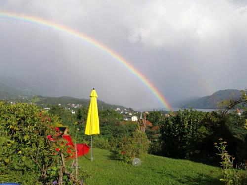 a rainbow over a garden with a umbrella at Apartments Krista in Seeboden