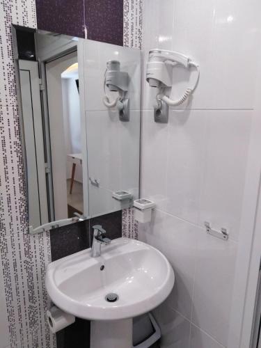 a white bathroom with a sink and a mirror at Guest House Harmony in Veliko Tŭrnovo
