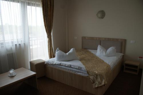 a bedroom with a bed with white pillows and a window at TROPHAEUM TRAIANI in Adamclisi