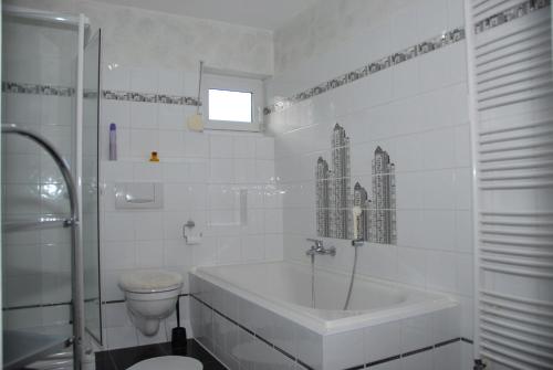 a white bathroom with a tub and a toilet at Haus Kölsch in Kröppen