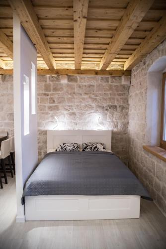 a bedroom with a bed in a brick wall at Limestone Heritage House in Trogir