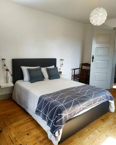 a bedroom with a bed with a blue and white comforter at Quinta da Regadas in Arouca