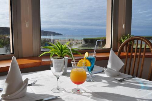 a table with two glasses of orange juice and a window at Hôtel de la Baie des Trépassés in Plogoff