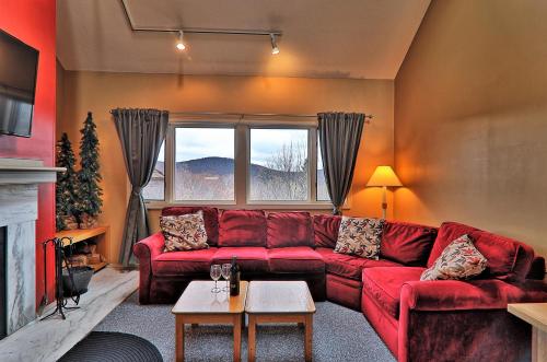 a living room with a red couch and a fireplace at Cozy,1 bedroom loft condo! Ski back trails, shuttle& Sports center Highridge E11 in Killington