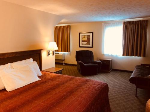 a hotel room with a bed and a chair at Shenandoah Inn & Suites in Shenandoah