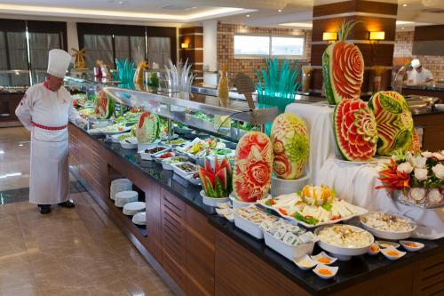 een chef-kok die voor een buffet staat met eten bij Diamond Hill Resort Hotel in Alanya