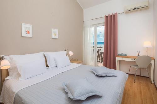 a white bedroom with a bed and a desk and a window at Lavica Seaside Apartments, Podstrana in Podstrana