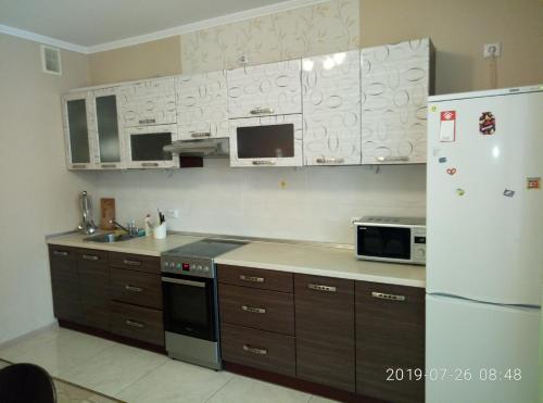 een keuken met houten kasten en een witte koelkast bij Люкс апартаменты на Позняках in Kiev