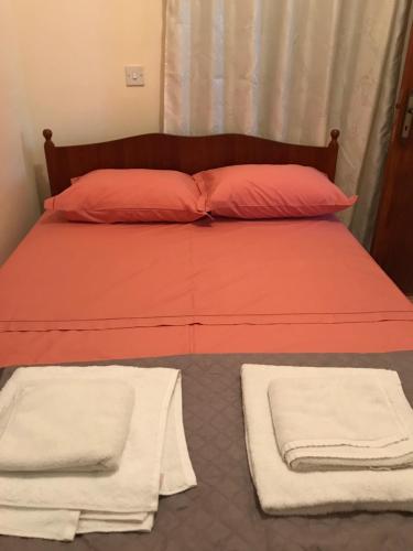 a bed with orange sheets and white towels on it at Pomos Small Sunny House in Pomos