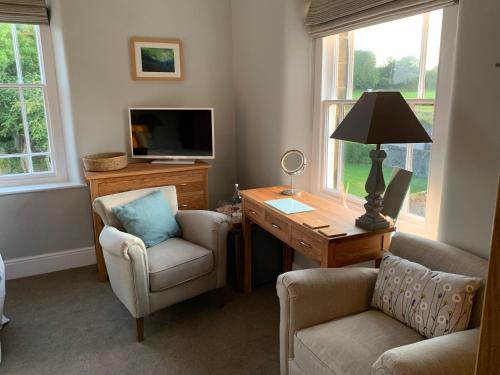 a living room with a desk and chairs and a tv at Hassop Station rooms on the Monsal Trail in Bakewell