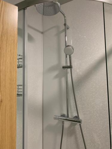 a shower with a glass door with a shower head at Hassop Station rooms on the Monsal Trail in Bakewell