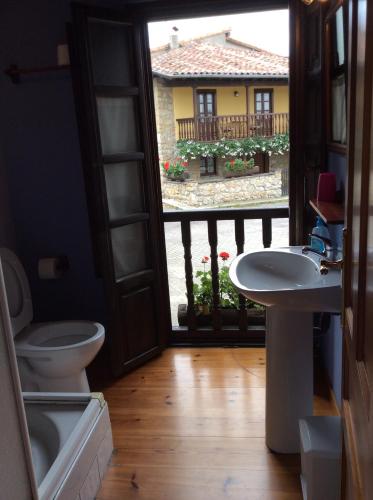 a bathroom with a toilet and a sink and a window at La Foina in Ceceda de Abajo