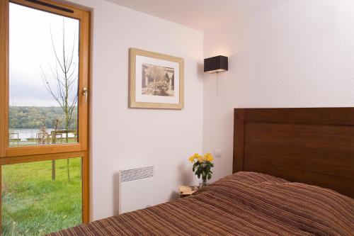 ein Schlafzimmer mit einem Bett und einem großen Fenster in der Unterkunft Madame Vacances Les Cottages De Valjoly in Eppe-Sauvage