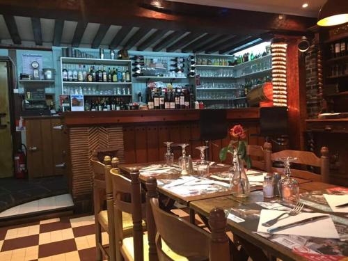a dining room with a table and a bar at Hotellerie Normande in Dozulé