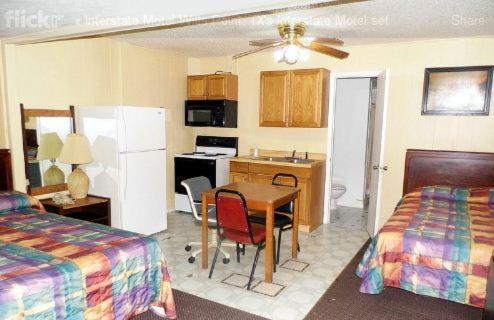 a hotel room with a table and a kitchen with two beds at Interstate Motel in Wills Point