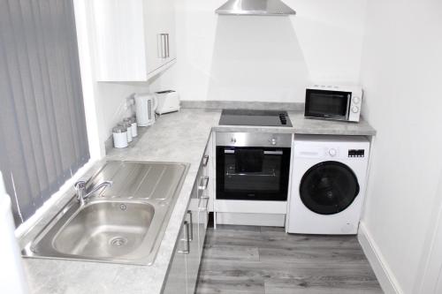 a kitchen with a sink and a washing machine at Reads Jacuzzi Suites & Apartments in Blackpool