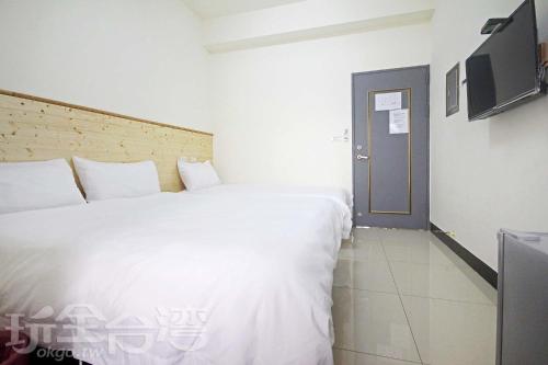 a bedroom with a large white bed and a door at 海豐民宿 Haifeng Bed and Breakfast in Jincheng