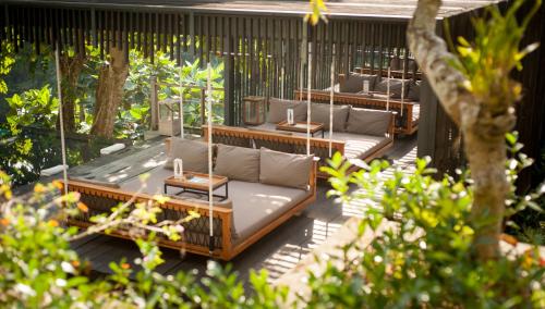 a patio with couches and tables in a garden at Chapung Sebali Resort in Ubud