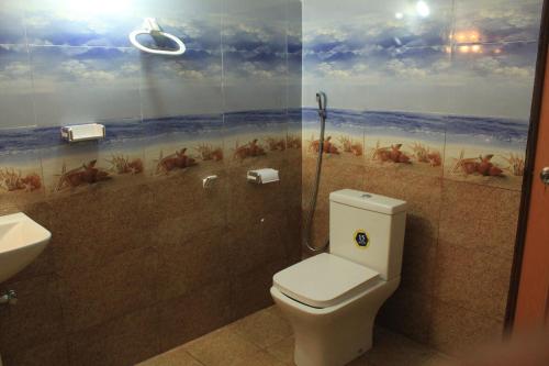 a bathroom with a toilet and a painting on the wall at Nature Night Homestay in Sigiriya